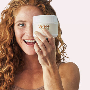 wavy red hair woman holding up verelle wavy curl cream with one hand