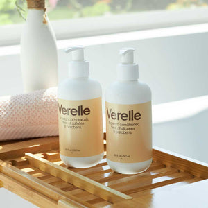 Verelle shampoo and conditioner sitting on a bathtub tray on a 